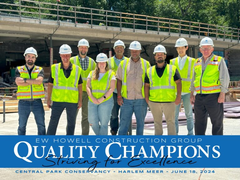 A group of nine construction workers wearing hard hats and safety vests stand side by side at a building site. Text below reads: “EW Howell Construction Group Quality Champions: Striving for Excellence. Central Park Conservancy - Harlem Meer - June 18, 2024.”.
